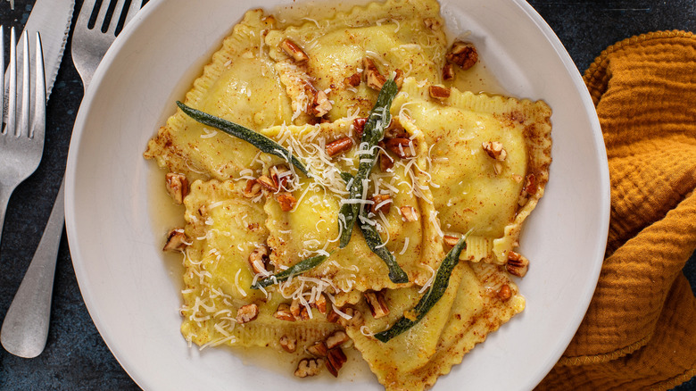 A plate of pumpkin ravioli, pecans, and crispy sage