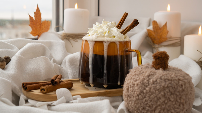 A mug of pumkin spice latte with autumnal decoration and cinnamon sticks