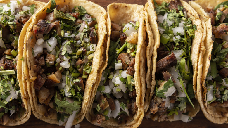 Top down view of tacos filled with meat, veggies, and herbs