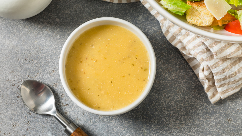 Bowl of creamy dressing next to salad and spoon