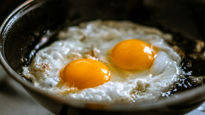 Close up of two eggs frying in skillet