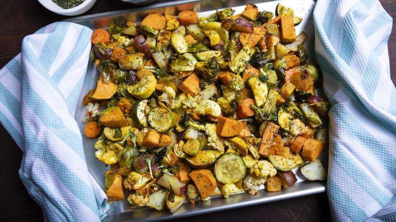 Roasted vegetables on sheet pan on top of blue striped linen