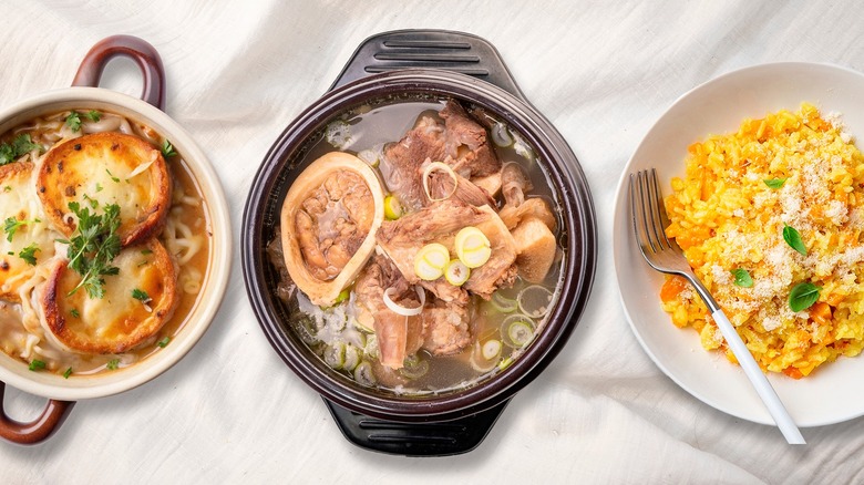 Three casserole dishes of French onion soup, stew and risotto on a table