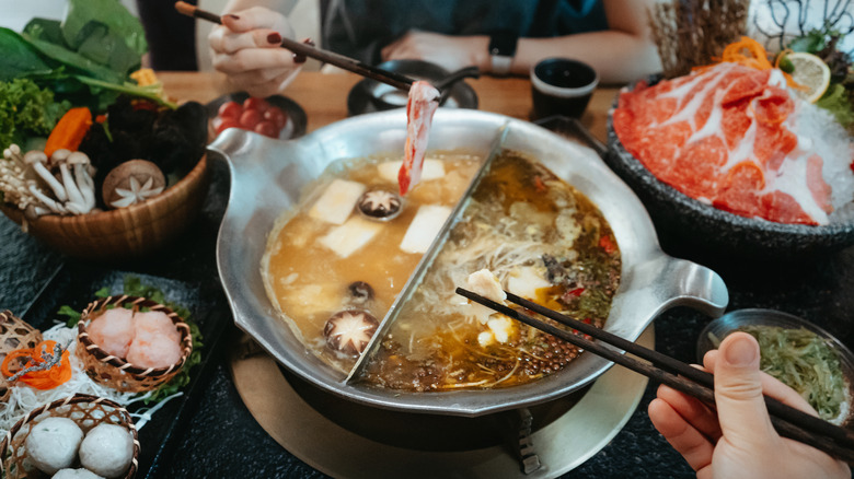 Two people having Chinese hot pot on a table full of ingredients
