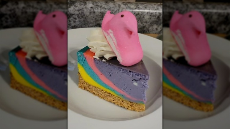 Slice of multicolored cheesecake topped with Easter Peep and whipped cream