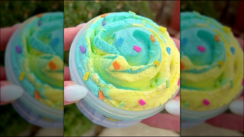 Hands holding tub of blue and yellow swirled Peeps ice cream