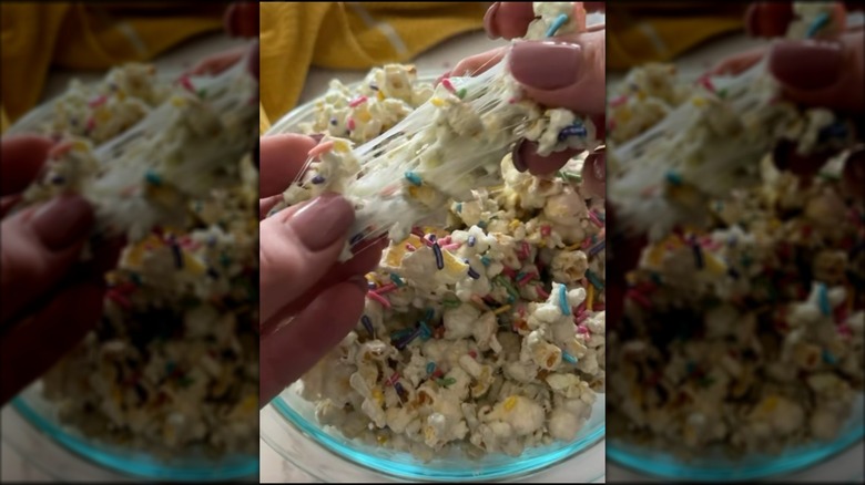 Hands pulling apart clump of marshmallow-covered popcorn