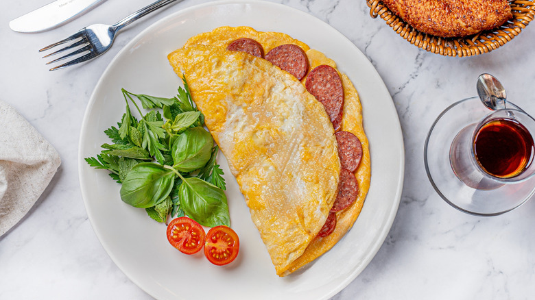 Pepperoni-filled omelet on plate with fresh salad