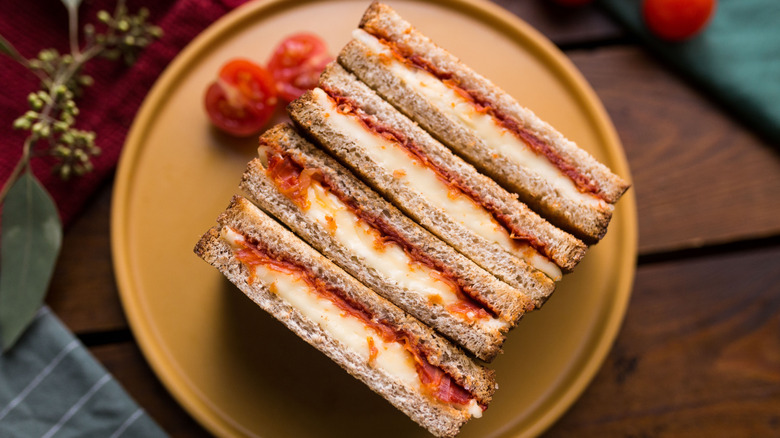 Row of halved grilled cheese and pepperoni sandwiches on yellow plate