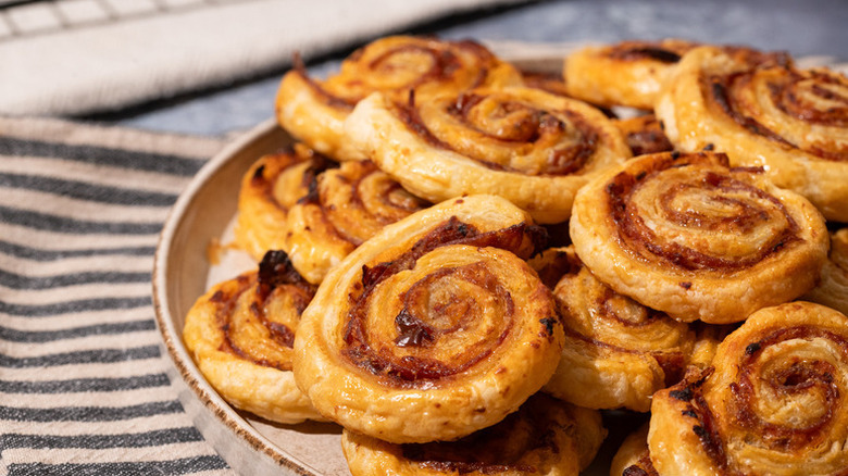 Pile of muffuletta pinwheels on plate next to striped linen