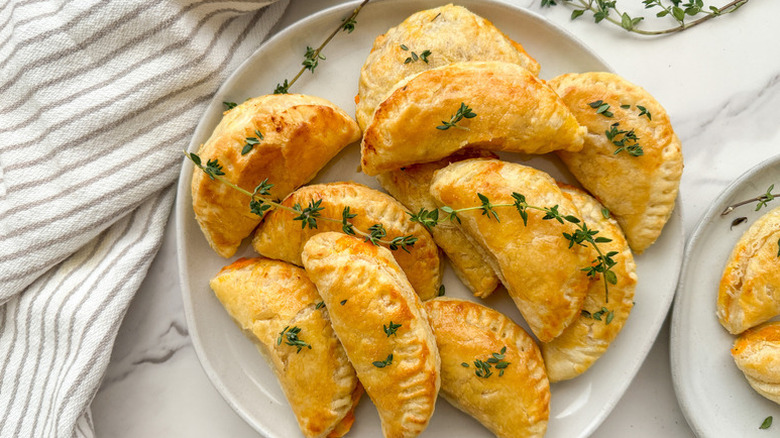 Pile of hand pies on plate with sprigs of fresh thyme