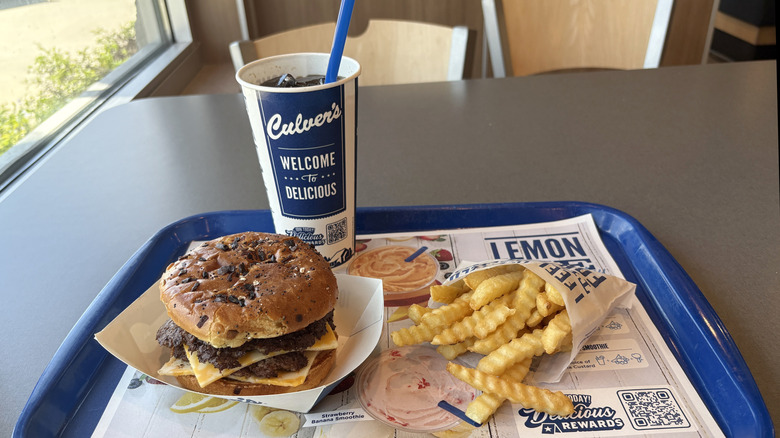 Burger, crinkle fries, and a soft drink in a Culver's cup sitting on a blue tray