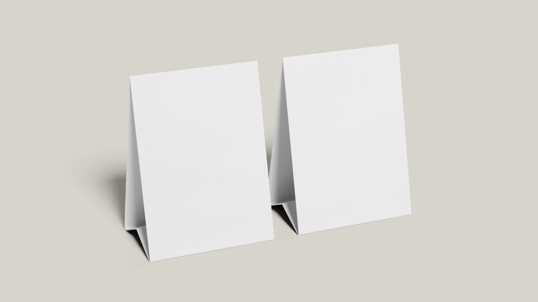 Two blank white table tents side by side on a beige backdrop