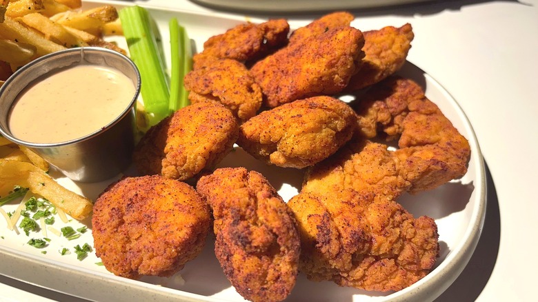 Dave & Buster's Chili Lime wings, sauce, and celery sticks on white plate on white table