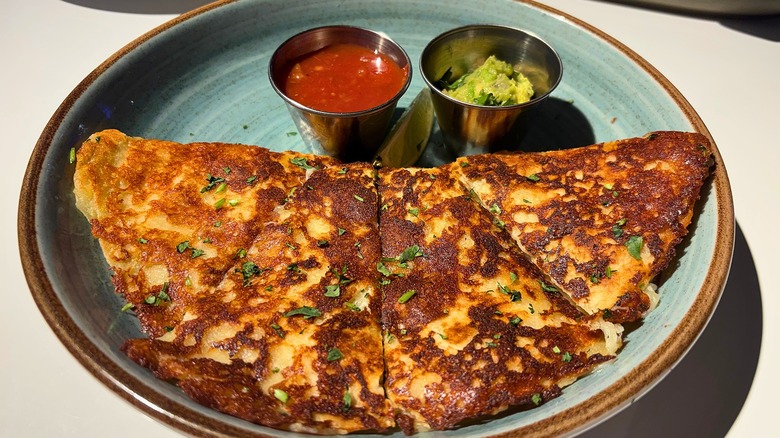 Dave & Buster's Grilled Chicken Quesadilla, salsa, guacamole on blue plate on white table