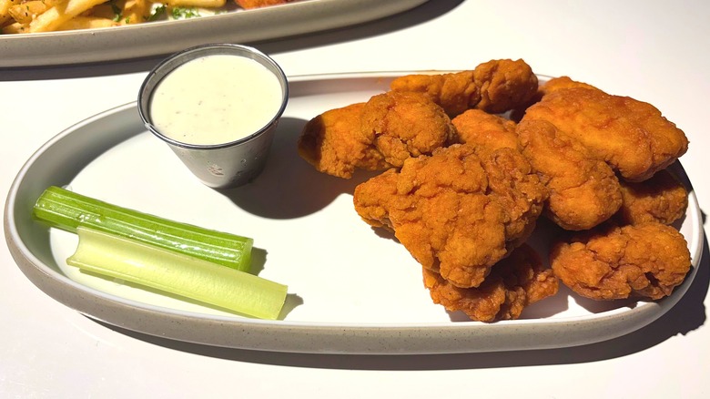 Dave & Buster's Habanero Wings, ranch, and celery sticks on white plate on white table