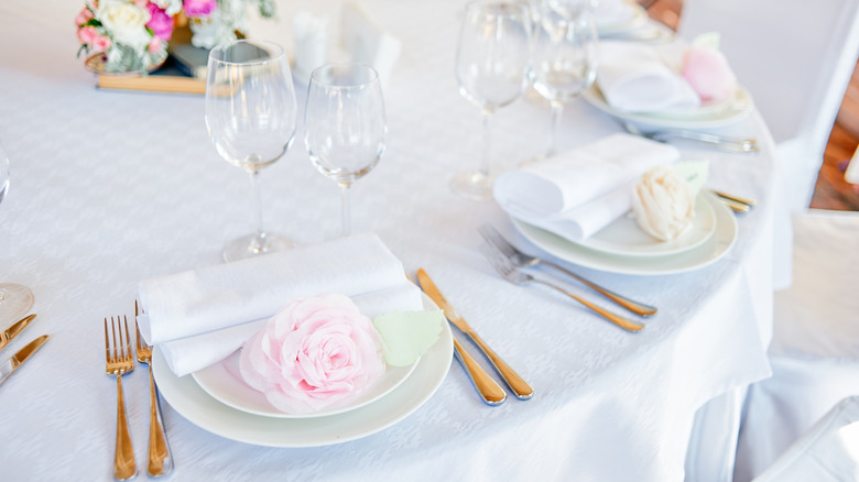 A formal table decorated with polished cutlery, wine glasses, and floral arrangements