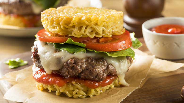 Ramen burger with melted cheese, lettuce, and tomato slices