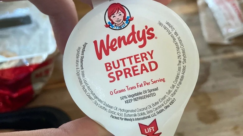 Hand holding packet of Wendy's buttery spread
