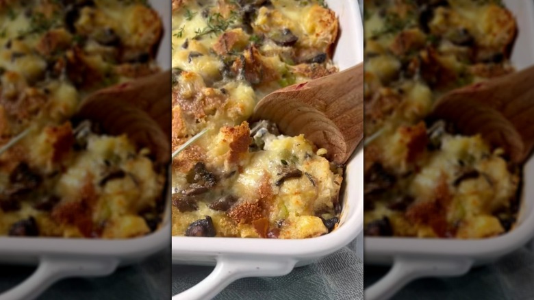 Close up on savory bread pudding in baking dish with wooden spoon
