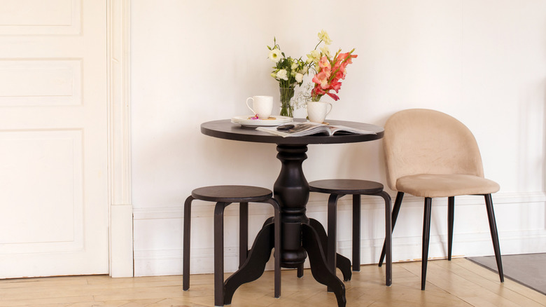 Black table and stools placed next to beige chair