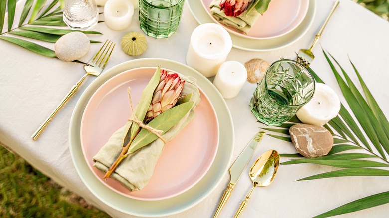 Spring-themed table setting with gold spoon and knife on one side of the plate and a fork on the other