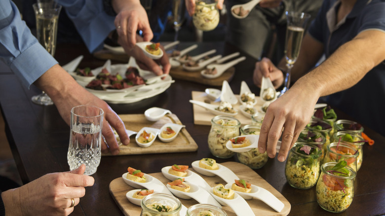 A crowded group of people taking food items from a buffet table