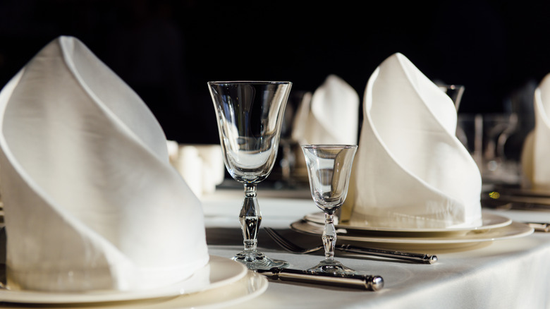 White napkin sculptures placed on white plates in a formal table setting