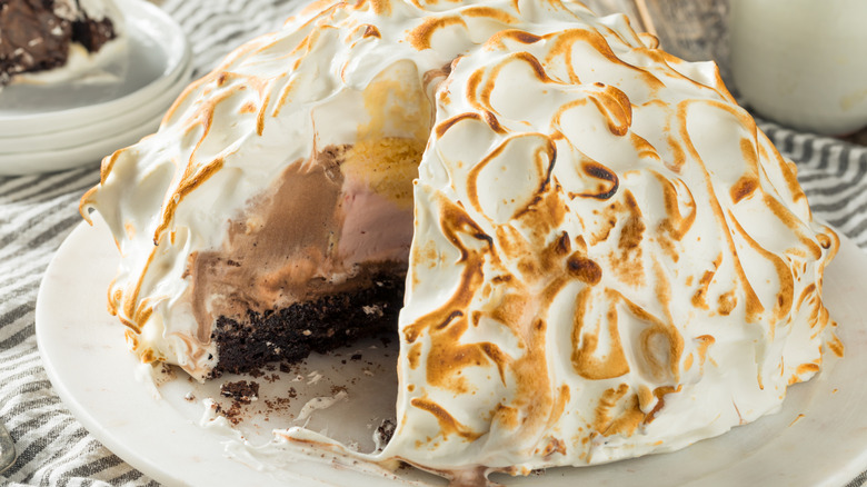 Baked Alaska dessert on plate, with slice taken out