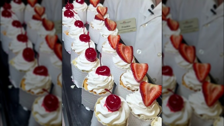 Baker holding Charlotte Russe cakes lined up on tray