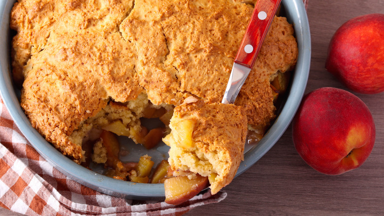 Spooning peach cobbler out of baking pan