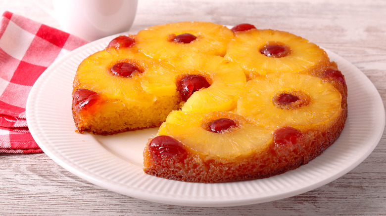 Pineapple upside-down cake on white plate, with slice taken out