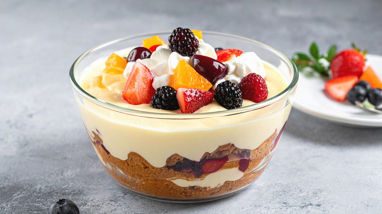 Bowl of trifle with layers of custard and cake, topped with fresh fruit