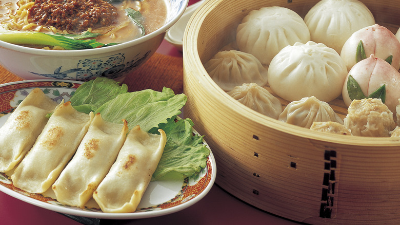 A close up of an array of Chinese dumplings served on plates and bowls