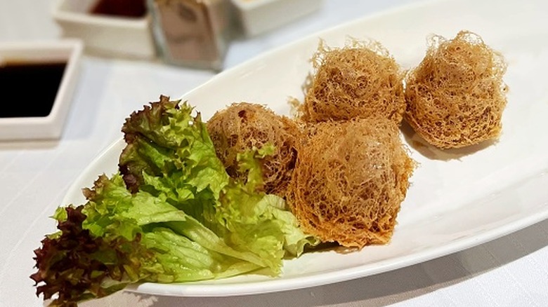 Dumplings with a lacey texture next to lettuce