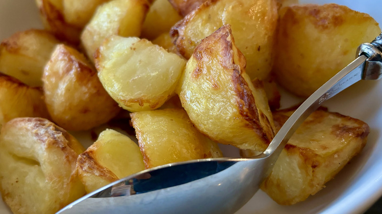 Crispy roast potatoes in bowl with spoon