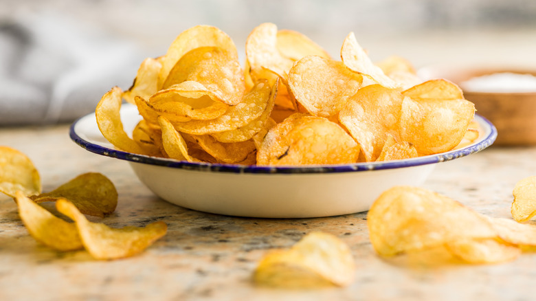 Potato chips in bowl with some spilling out