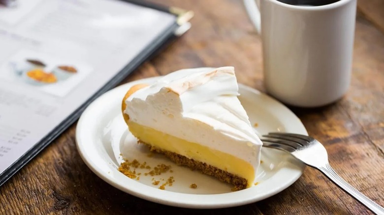 Slice of Dwarf House lemon pie sitting on saucer next to coffee mug and menu