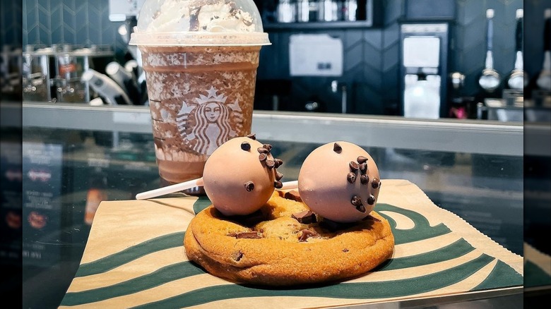 Starbucks cookie dough cake pop with a cookie and coffee inside a Starbucks shop
