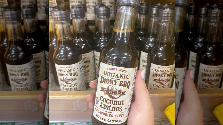 Hand holding bottle of Organic Smokey BBQ Flavored Coconut Aminos