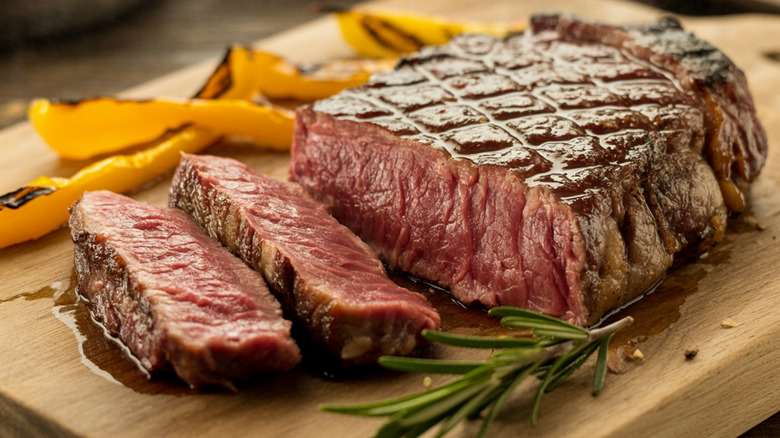 Rare sliced steak on a cutting board with rosemary sprig