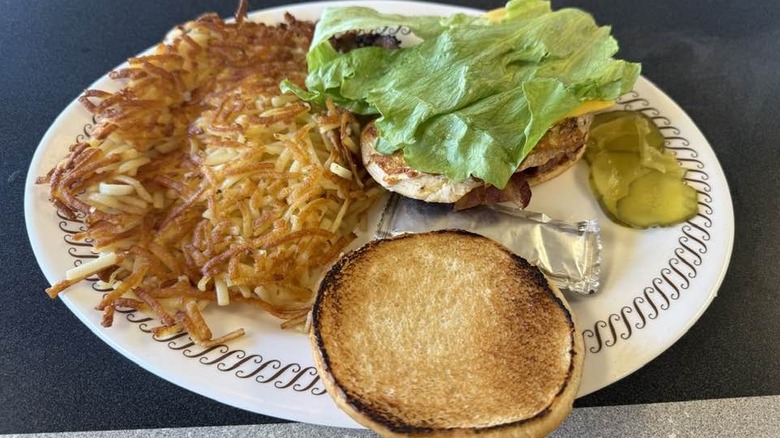 Grilled chicken sandwich with hash browns on white plate at Waffle House