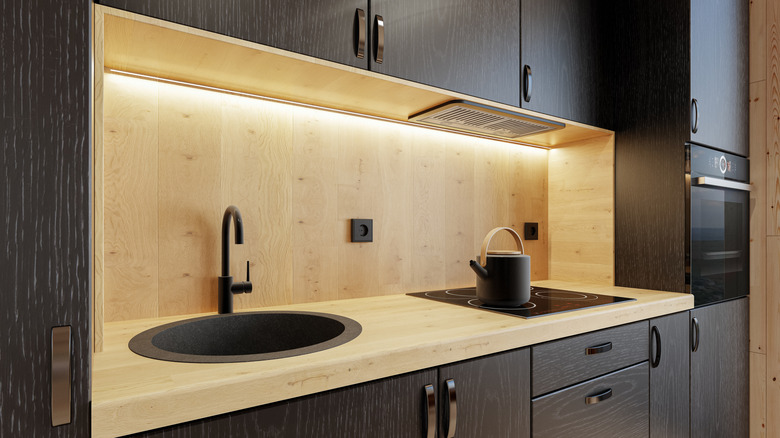 Black kitchen cabinets illuminated with under-cabinet strip lighting