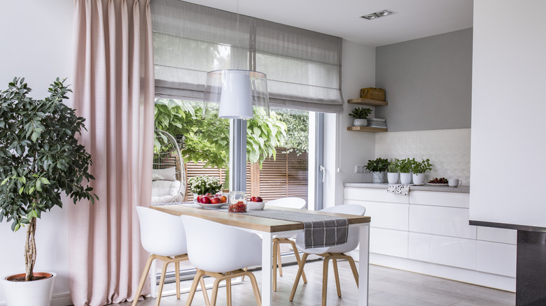 Grey Roman shades and pink curtains against the large window of a modern kitchen