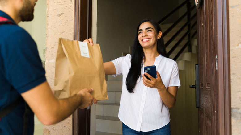 Person accepting food delivery bag from driver