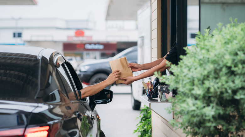 Hands handing someone bag of food at drive thru