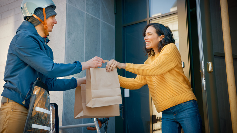 Food delivery worker handing bag to customer