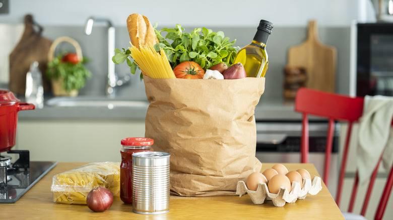 Groceries in paper bag on wooden table