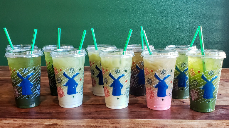 Ten matcha drinks from Dutch Bros on a wooden table.