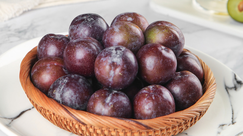 Fresh red plums arranged in a woven basket